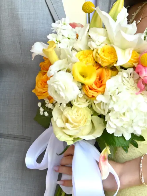 Bouquet of yellow roses, white calla lilies, craspedia and hydrangea tied with a white ribbon