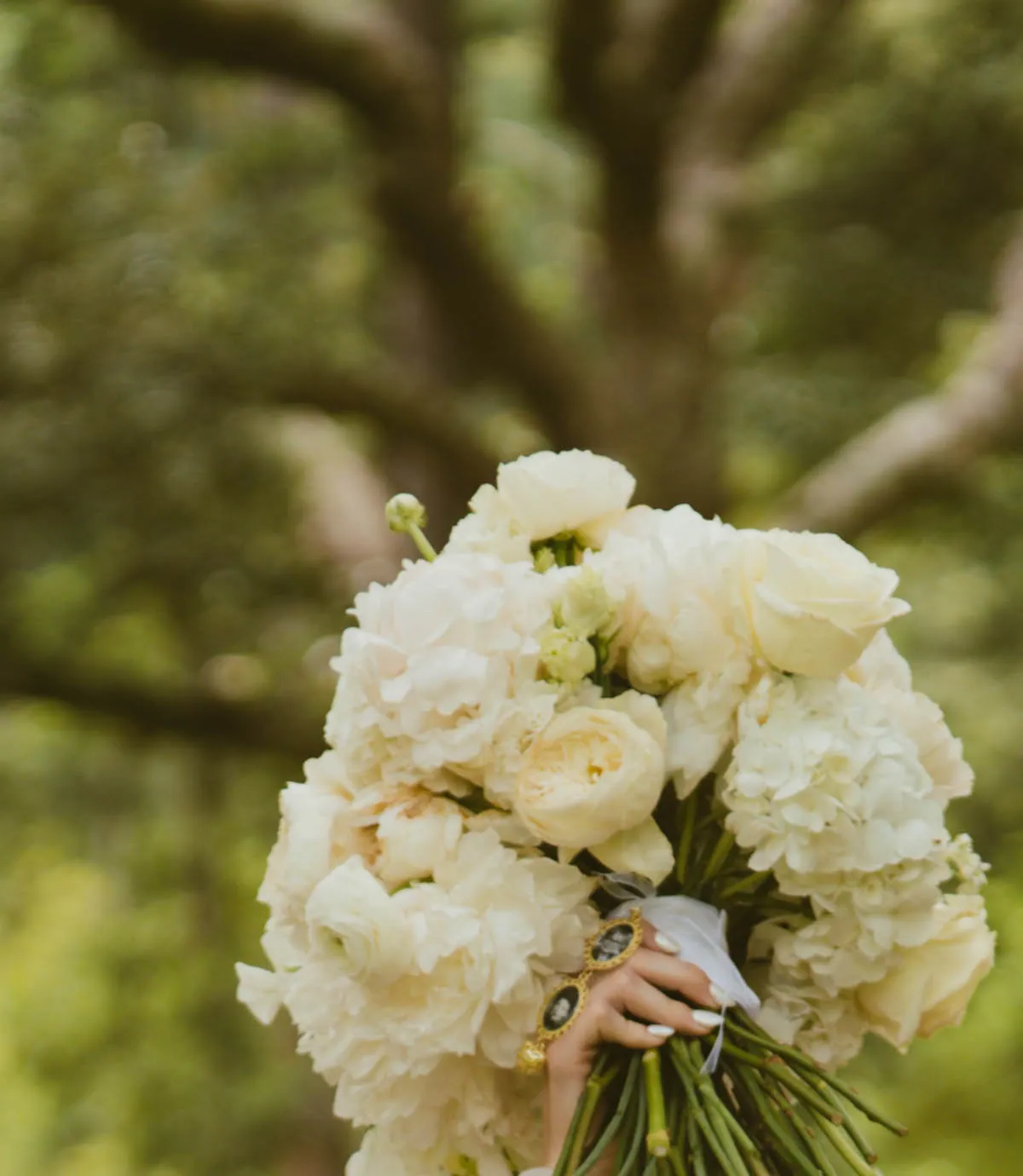 White garden rose and peony bouquet lifted overhead by a bride surrounded by her bridesmaids